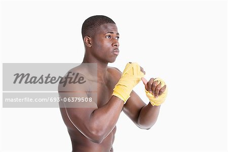 Shirtless African American kickboxer over gray background