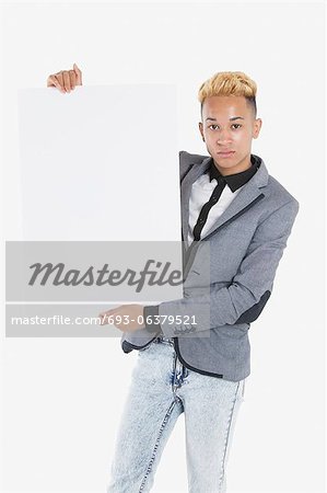 Portrait of a young man holding blank cardboard over gray background