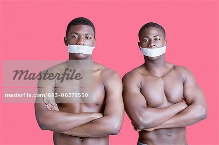 Portrait de deux hommes afro-américains musculaires avec rubans couvrant la bouche sur fond rose