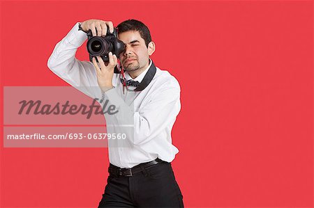 Race mixte homme prise de photo avec appareil photo numérique sur fond rouge