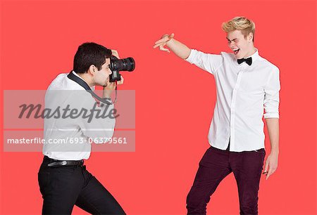 Male actor being photographed by paparazzi over red background