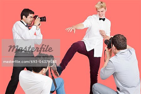 Paparazzi taking photographs of male actor over red background