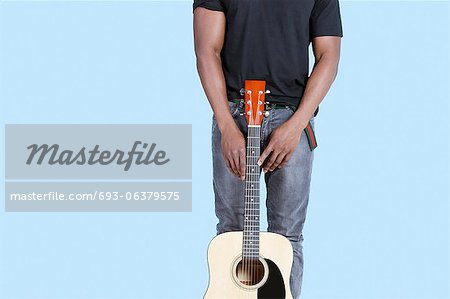 Mid section of an African American man with guitar over light blue background