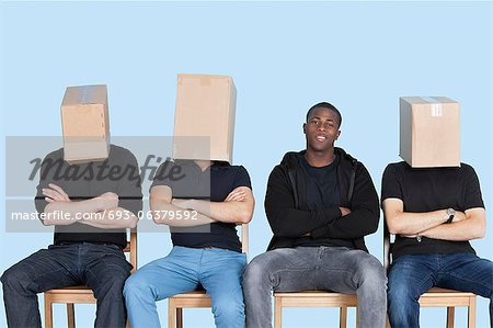 Homme avec des visages amis recouvert de cartons comme ils sont assis sur une chaise sur fond bleu