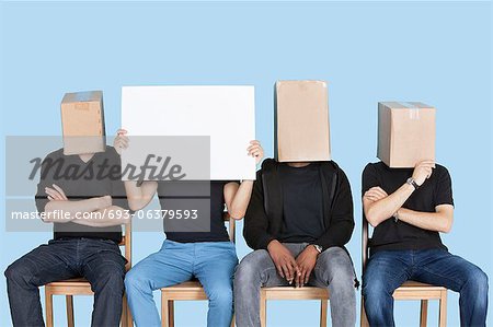 Homme tenant un carton blanc avec des visages d'amis de sexe masculin recouvert de boîtes sur fond bleu