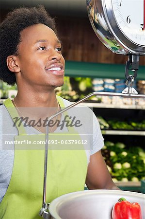 Afroamerikaner männlichen Verkäuferin mit einem Gewicht von Paprika