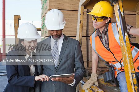 Engineers and female industrial worker looking at tablet PC