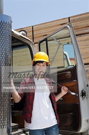 Portrait of an Asian female industrial worker standing by vehicle door