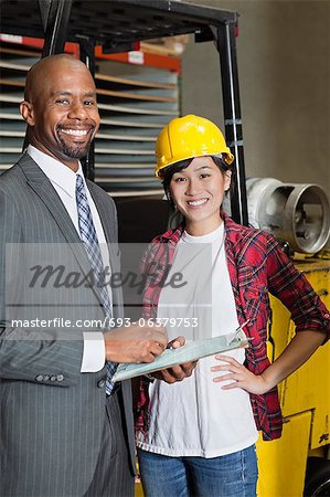 Portrait of female industrial worker standing with male inspector