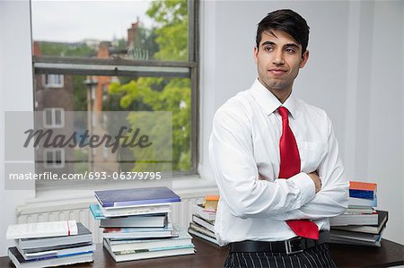 Portrait of a confident businessman with arms crossed looking away in office