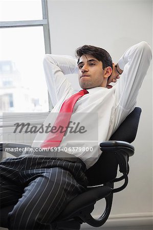 Young Indian businessman contemplating while sitting in office chair