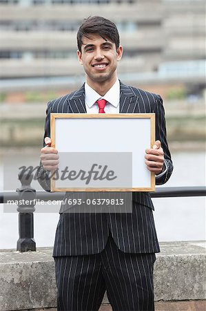 Portrait de jeune homme d'affaires indien, tenant une pancarte blanche