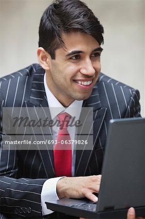 Young smiling Indian businessman using laptop