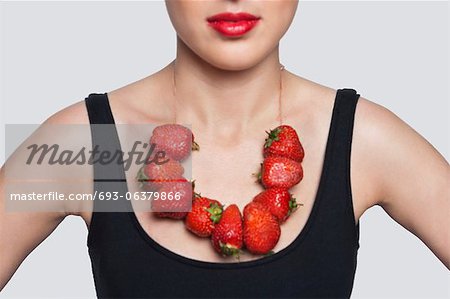 Mitte-Abschnitt einer Frau, der Erdbeeren Halskette über den grauen Hintergrund