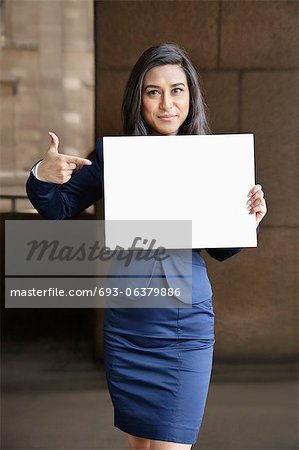 Portrait of a young Indian businesswoman pointing towards Moodboard sign Portrait of a young Indian businesswoman pointing towards Moodboard sign