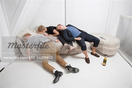 Drunk male friends sleeping on fur sofa after party