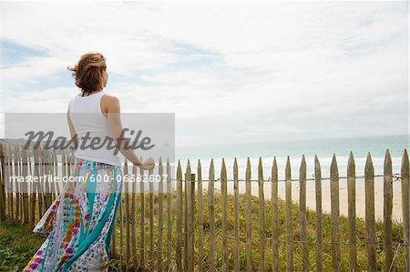 Woman Leaning on Sandfence am Strand, Camaret-Sur-Mer, Halbinsel Crozon, Finistere, Bretagne, Frankreich