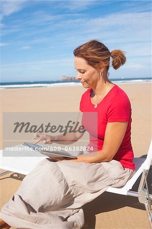 Woman Using Tablet at the Beach, Camaret-sur-Mer, Crozon Peninsula, Finistere, Brittany, France