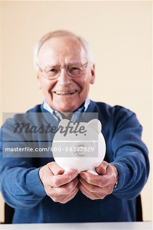 Portrait of Senior Man Holding a Piggy Bank