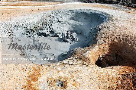 Mudpot dans la zone géothermique Hverir, Islande. Les environs de la boue bouillante sont multicolore et craquelée.