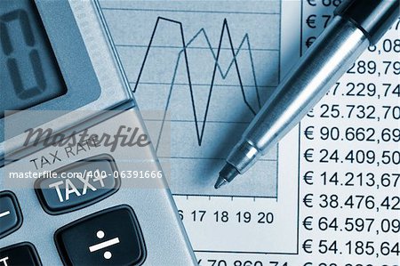 Detail of calculator, focusing the TAX key, next to a sheet of paper with numbers and a metal pen