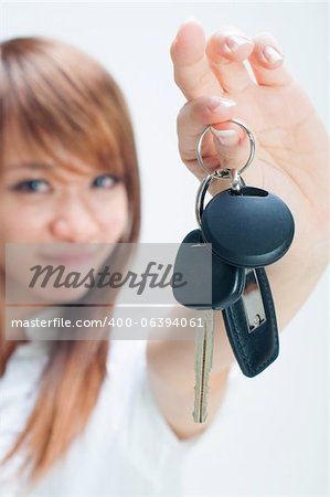 Jeune femme tenant sa première clé propre voiture sur fond blanc, se concentrer sur les clés de voiture.