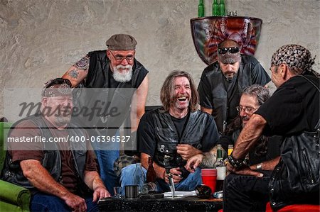 Six male biker gang members laughing with weapons on table