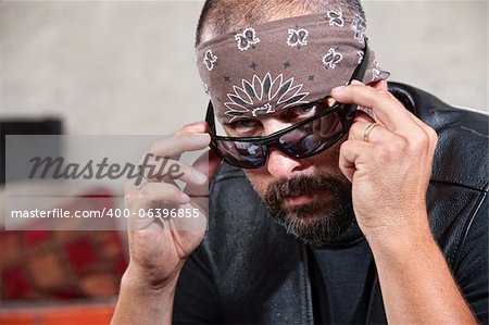 Intimidant biker masculin en bandana regarder par-dessus ses lunettes de soleil