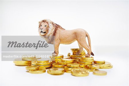 Toy lion on stacks of gold coins Toy lion on stacks of gold coins