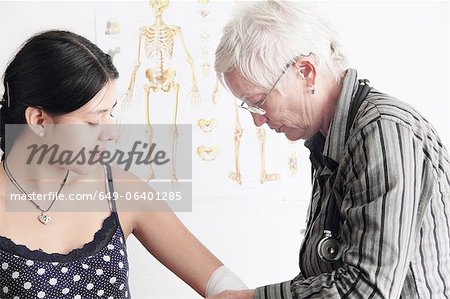 Doctor wrapping teenage girl's elbow