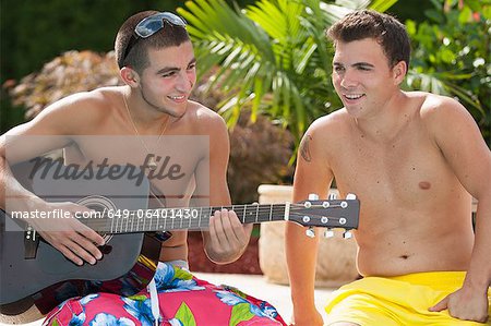 Teenage boys relaxing by swimming pool