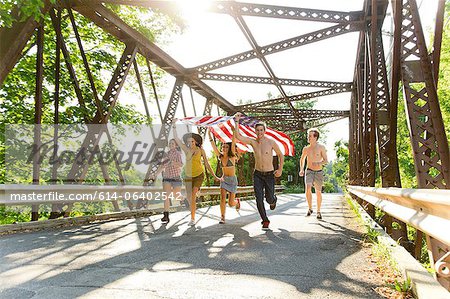 Group of friends running on bridge holding american flag