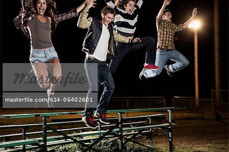 Four friends jumping over bleachers at night