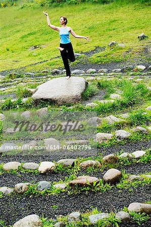 Woman in yoga pose on stone in maze