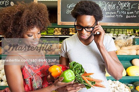 Young African American couple buying vegetables at supermarket