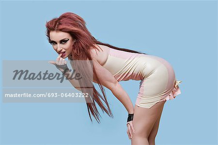 Portrait of seductive young funky woman bending over blue background