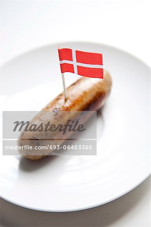 Fried sausage in plate with Danish flag decoration against white background Fried sausage in plate with Danish flag decoration against white background
