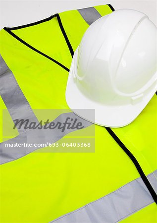 Safety vest and hard hat against white background