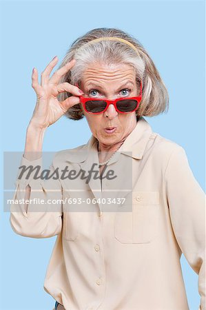Portrait of senior woman wearing sunglasses against blue background