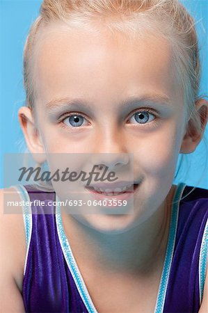 Close-up portrait of a young female gymnast over blue background