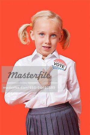 Portrait d'une jeune écolière avec badge vote sur fond orange
