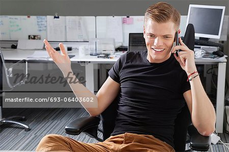 Heureux jeune homme à l'aide de téléphone portable au bureau