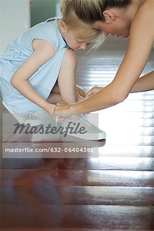 Mutter hilft der Tochter ihre Schnürsenkel binden