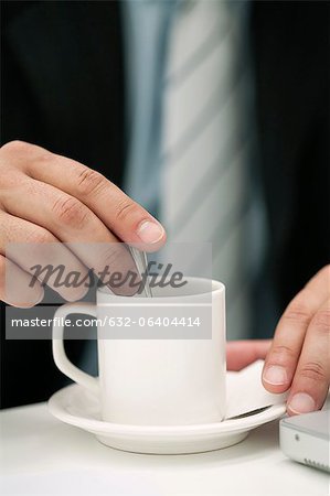 Man stirring cup of coffee, cropped