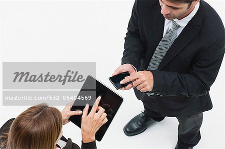 Businesswoman using digital tablet, businessman using smartphone