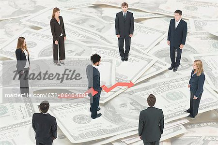 Executives standing on large pile of money around man holding arrow forecasting financial future