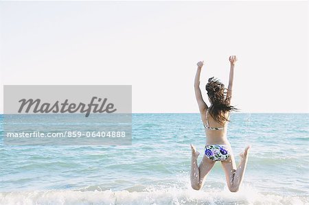 Japanische Frau im Bikini am Meer springen