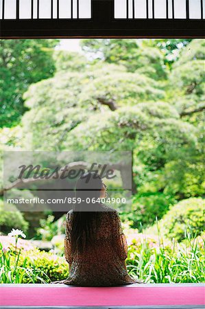 Japanische Frau sitzt beim Betrachten eines Gartens