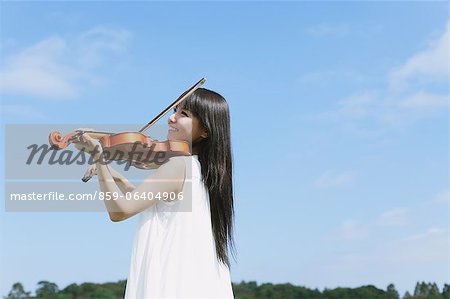 Asiatique femme jouant du violon avec ciel bleu en arrière-plan