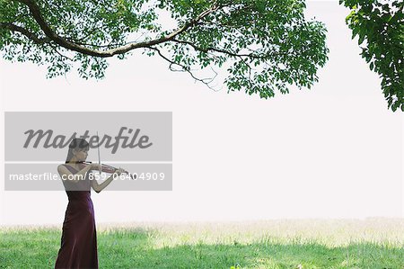 Asiatique femme jouant du violon dans un champ d'herbe